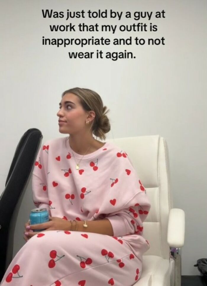 Woman in cherry-patterned outfit sits in office chair, reflecting on workplace attire guidelines. Woman in cherry-patterned outfit sits in office chair, reflecting on workplace attire guidelines.