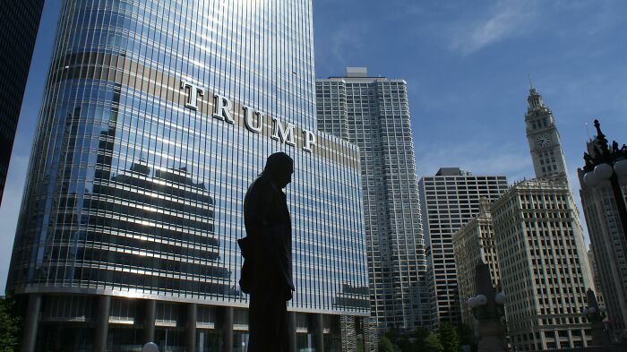 Silhouette of a statue in front of a building with "Trump" sign, capturing a pop culture moment.