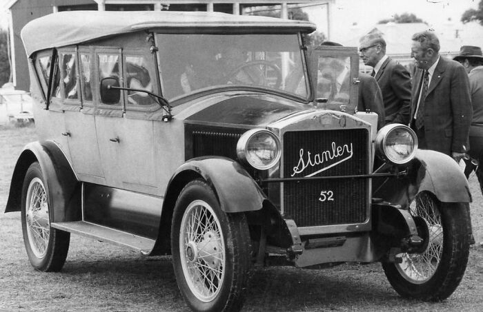 Vintage Stanley steam car with onlookers; an inventive creation that contributed to its inventor's downfall.
