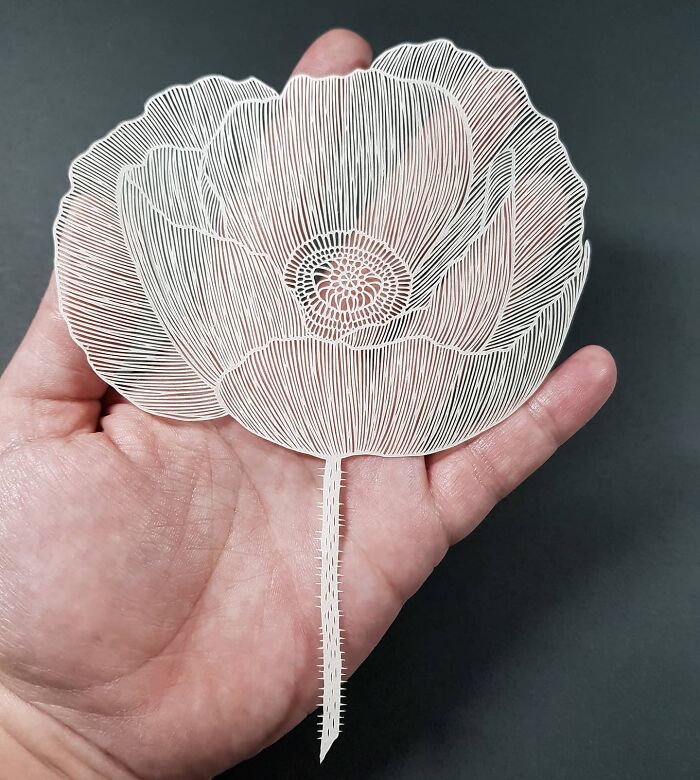 Intricate paper art design resembling a flower held in a hand, showcasing nature-inspired artistry.