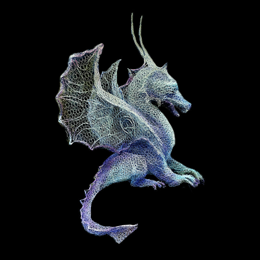Chicken wire dragon sculpture with detailed wings and horns, set against a black background, showcasing intricate craftsmanship.
