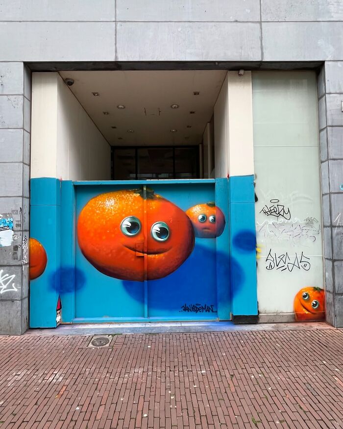 Hyperrealistic illusions by Jan Is De Man, featuring smiling oranges on a city wall.