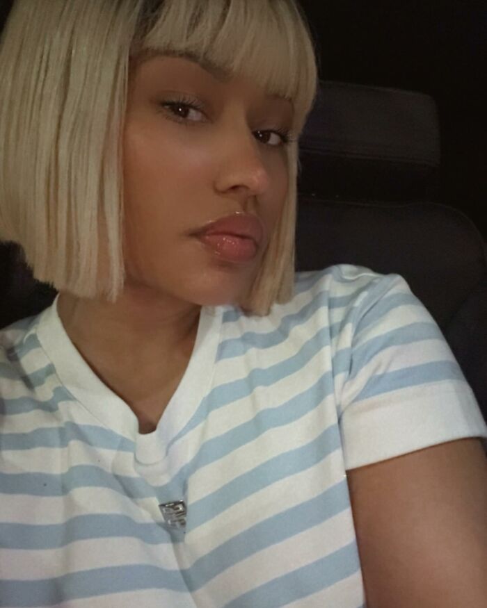 Person with blonde bob haircut in striped shirt, capturing a selfie. Celebrity insight theme.