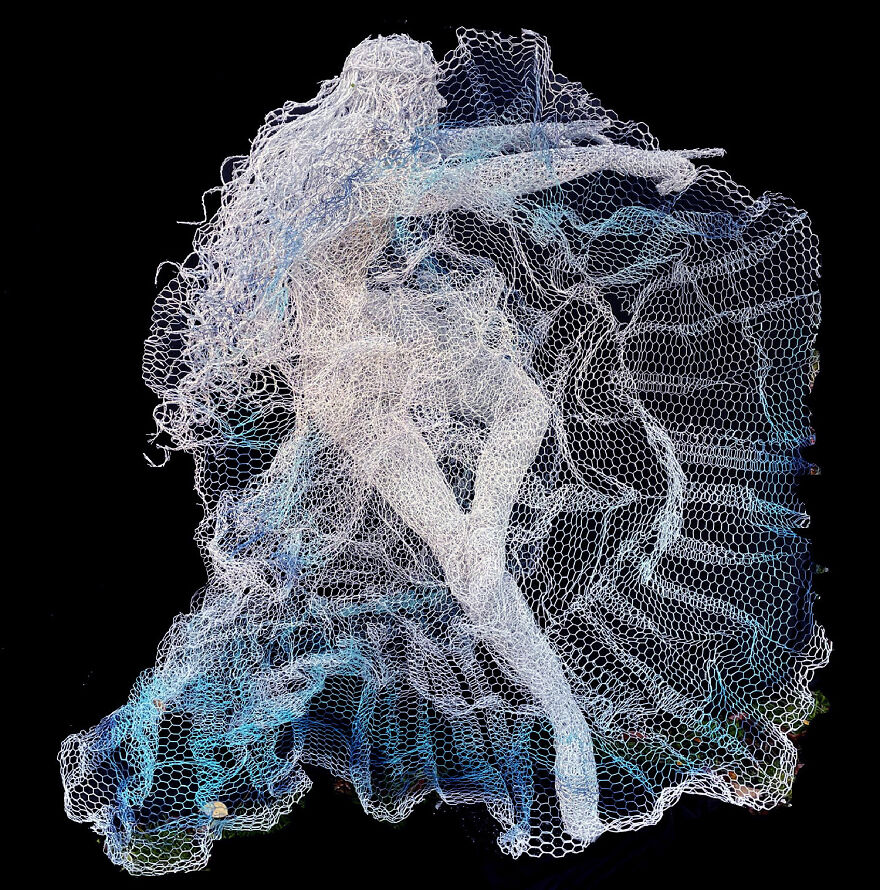 Chicken wire sculpture of a dancer in a dynamic pose against a black background.
