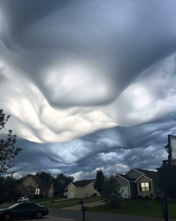 Unusual cloud formations over suburban houses, creating an interesting sky view.