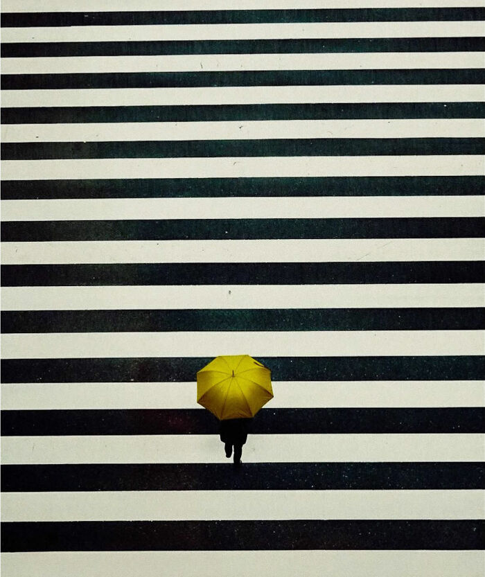 Minimalist Tokyo street scene with person holding a yellow umbrella, crossing striped pavement.
