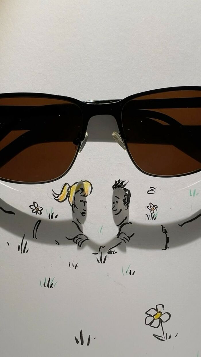 Sunglasses casting shadows transformed into an illustration of a couple lying on the grass.