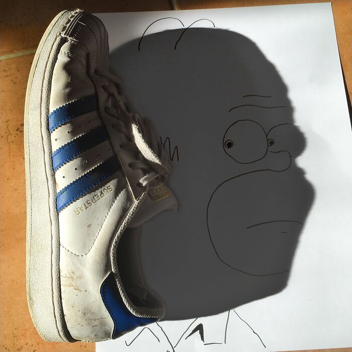 Shoe casts shadow resembling cartoon character, illustrating creative transformation by artist.