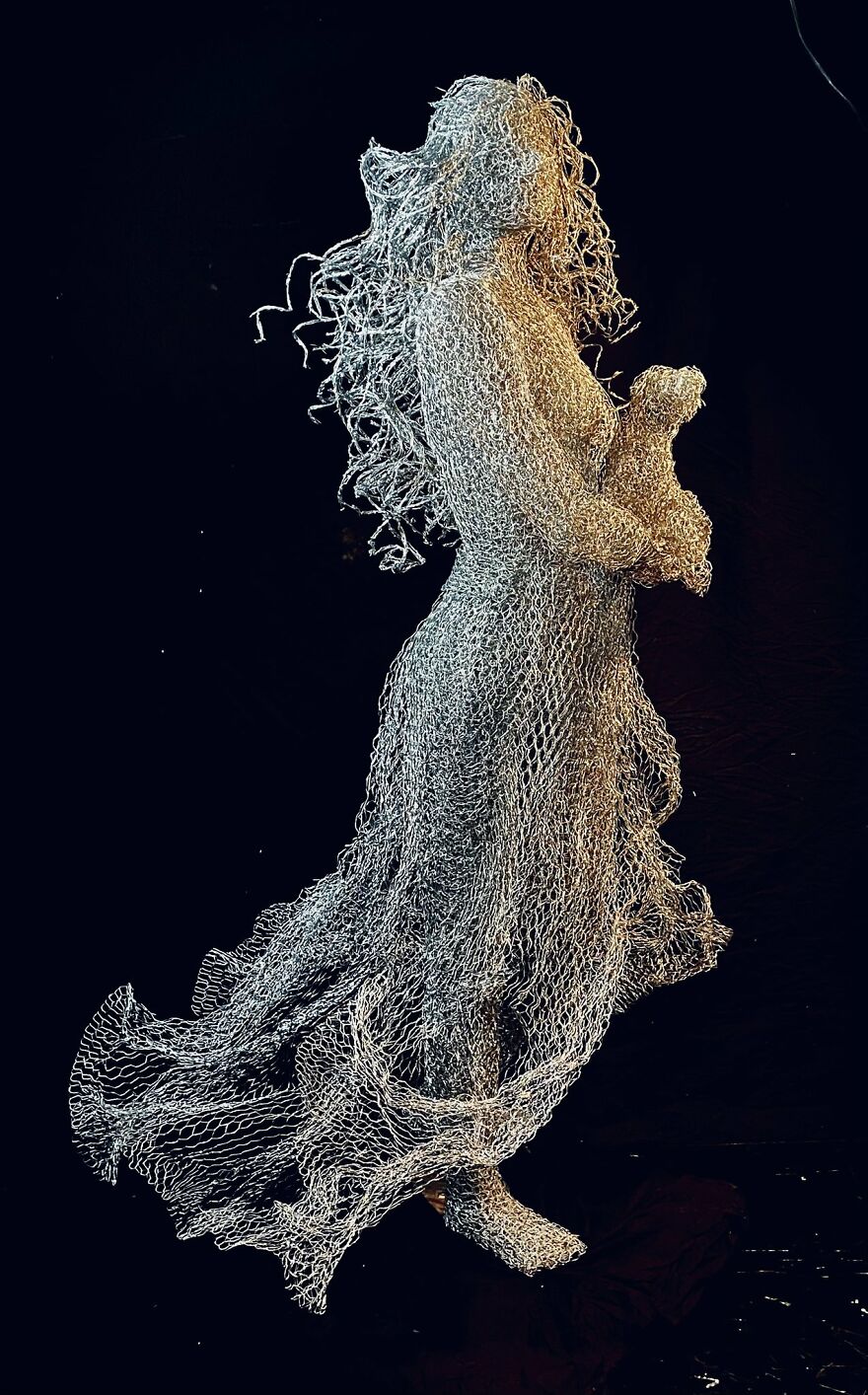 Chicken wire sculpture of a flowing figure, showcasing detailed artistry in a lifelike pose.