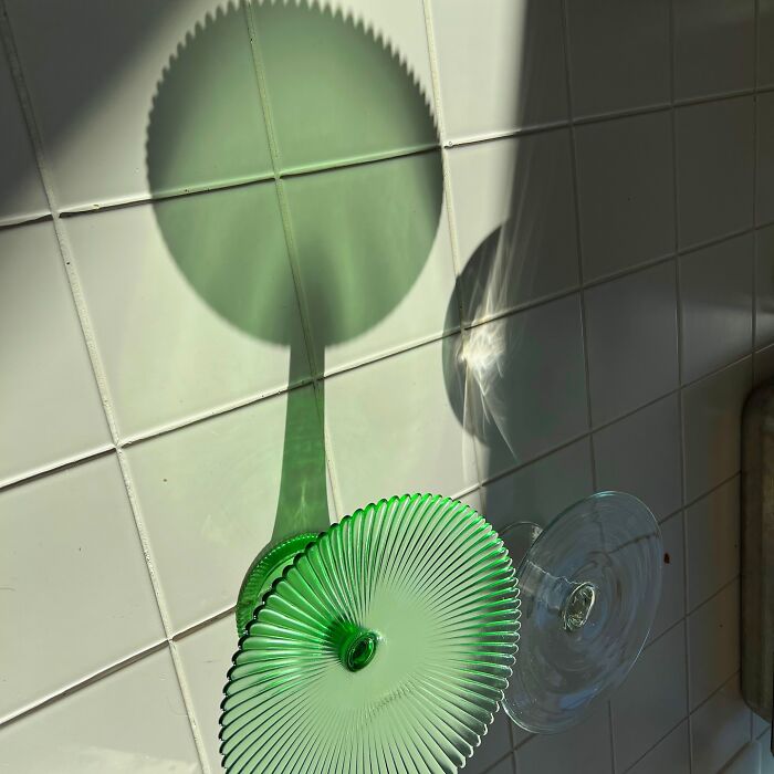 Shadow of a green glass object on a tiled wall, creatively transformed into an artistic illustration.