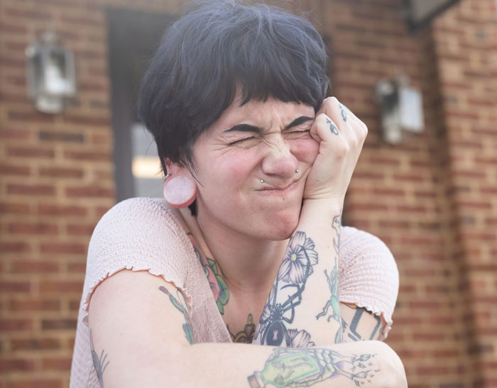Tattooed woman looking frustrated outside, related to vegan family conflict. Tattooed woman looking frustrated outside, related to vegan family conflict.
