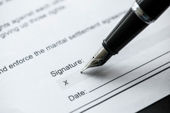 A pen signing divorce papers, highlighting unexpected consequences of a woman's joke.
