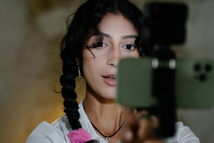 Woman recording herself with a smartphone, exploring safe side hustle ideas.