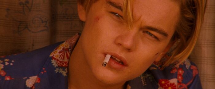 Young man in the 90s with a cigarette, wearing a floral shirt, looking contemplative.