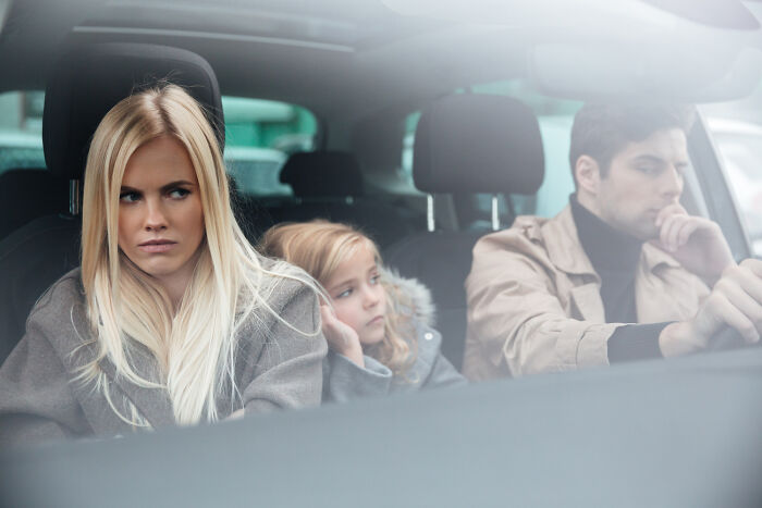A family in a car showing tense expressions, illustrating experiences people were raised to think were common.