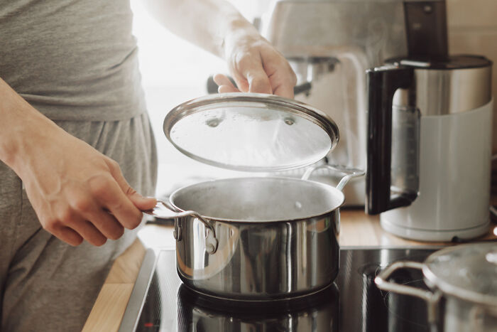 Person lifting lid off pot on stovetop demonstrating home cooking cheats.