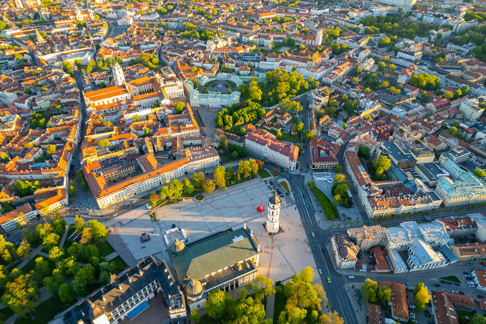 Bird’s-eye view of Vilnius, Lithuania showcasing historic buildings and green spaces bathed in sunlight.