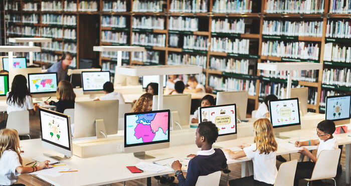 Children in a library using computers, illustrating rules implemented due to one individual.