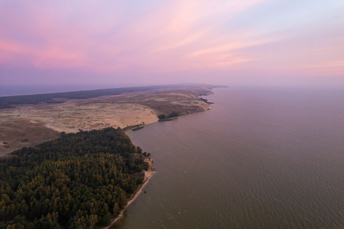 Bird's-eye view of Lithuania's beautiful coastline at sunset with pink skies.