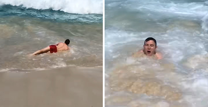 Man in red shorts on the beach struggling in the waves, depicting a humorous crisis moment.