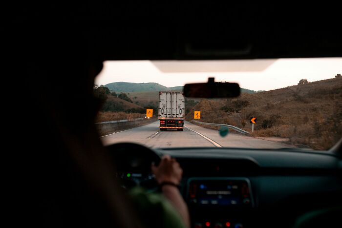 View from inside a car following a truck on a winding road, highlighting professions often underestimated.