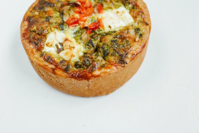 Savory mini quiche with spinach and tomatoes on a white background, representing bizarre things real men don't do.