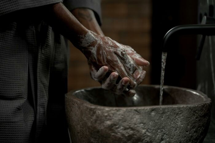 Person washing hands in a stone sink, symbolizing hygiene habits of deeply weird people.