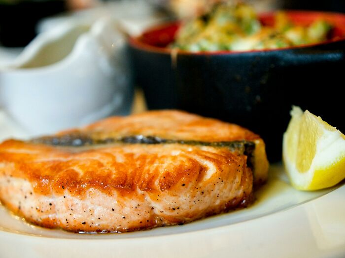Grilled salmon on a plate with vegetables, showcasing healthy eating challenges linked to fitness myths.