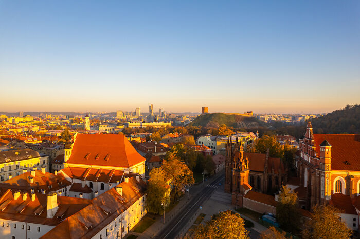 Lithuania bird’s-eye view of Vilnius with Gediminas Tower, showcasing vibrant cityscape and autumn colors at sunset.