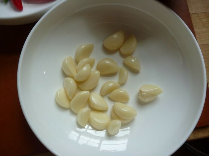 Peeled garlic cloves in a white bowl, showcasing a simple cooking cheat from home chefs.