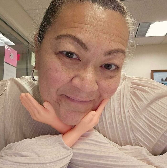 Person smiling with novelty toy arms under their chin, illustrating a fun impulse buy.