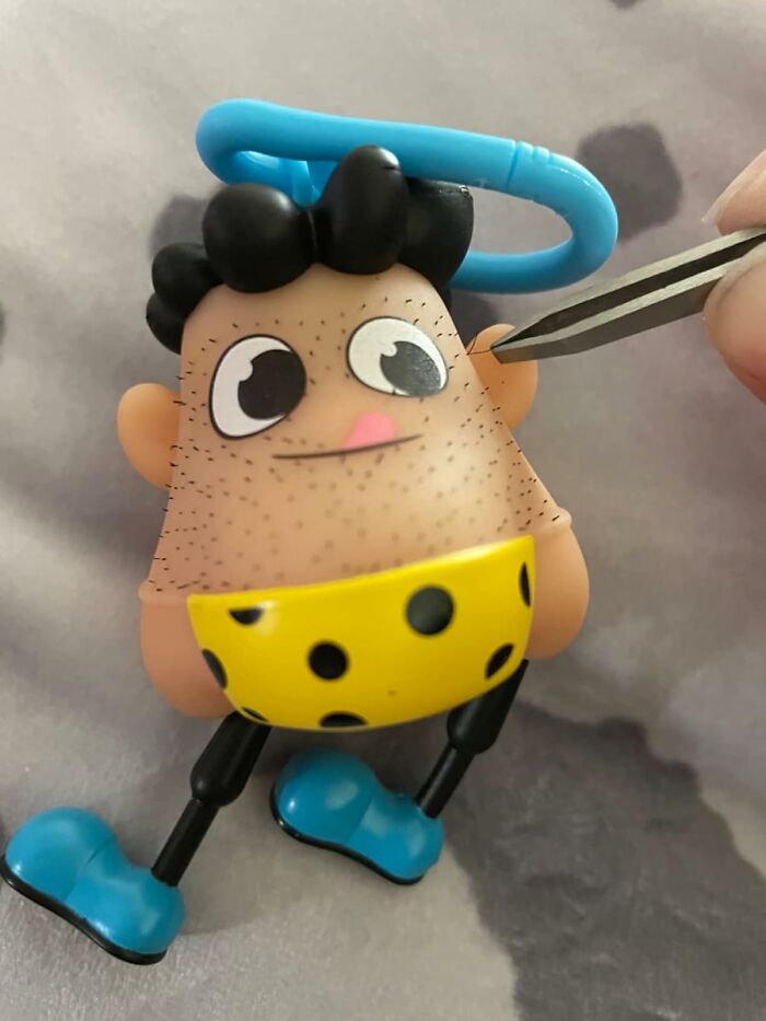 Cartoonish keychain toy with tweezers, showcasing unexpected goofiness with bright colors and playful design.