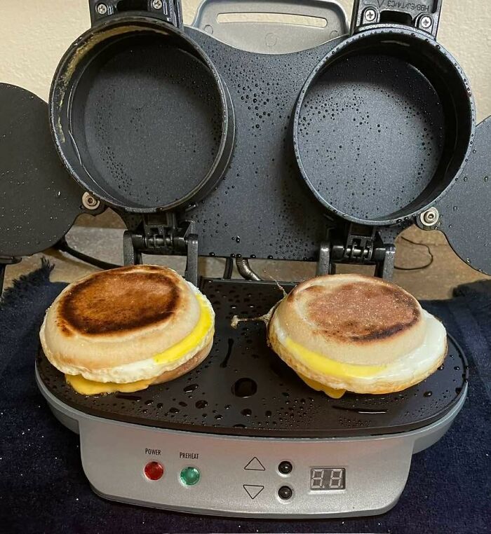 Sandwich maker with two breakfast muffins cooking, showcasing a long-term kitchen investment.