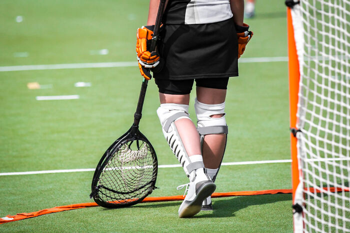 Field hockey goalie on turf, wearing protective gear and holding a stick, highlights individual influence on game rules.