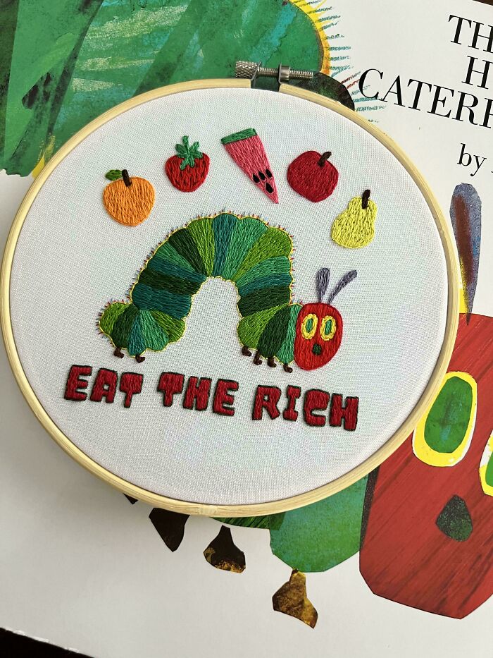 Colorful embroidery hoop featuring a caterpillar and fruits with bold text showcasing beautiful embroidery skills.