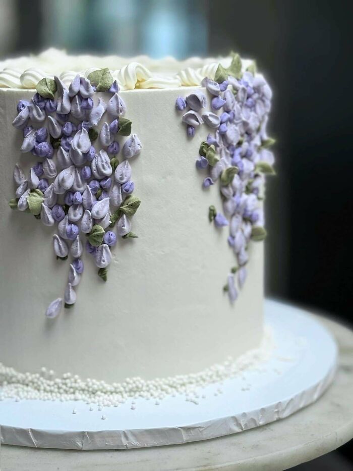 White cake decorated with intricate purple and green floral designs, showcasing one of the incredible bakes in spotlight.