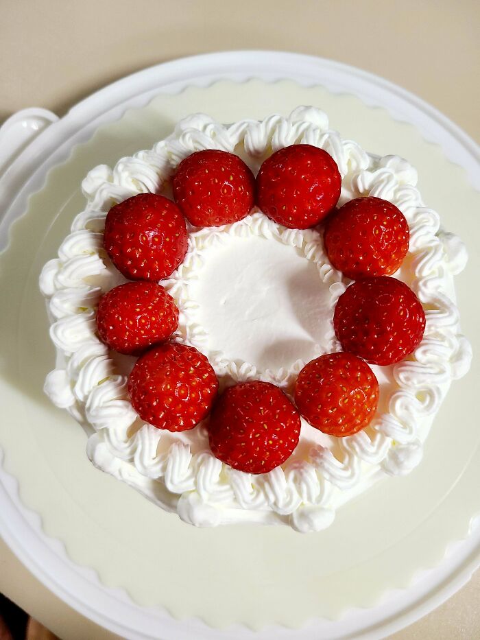 Strawberry topped cake with whipped cream decoration on a white plate, showcasing incredible bakes with fresh fruit accents.