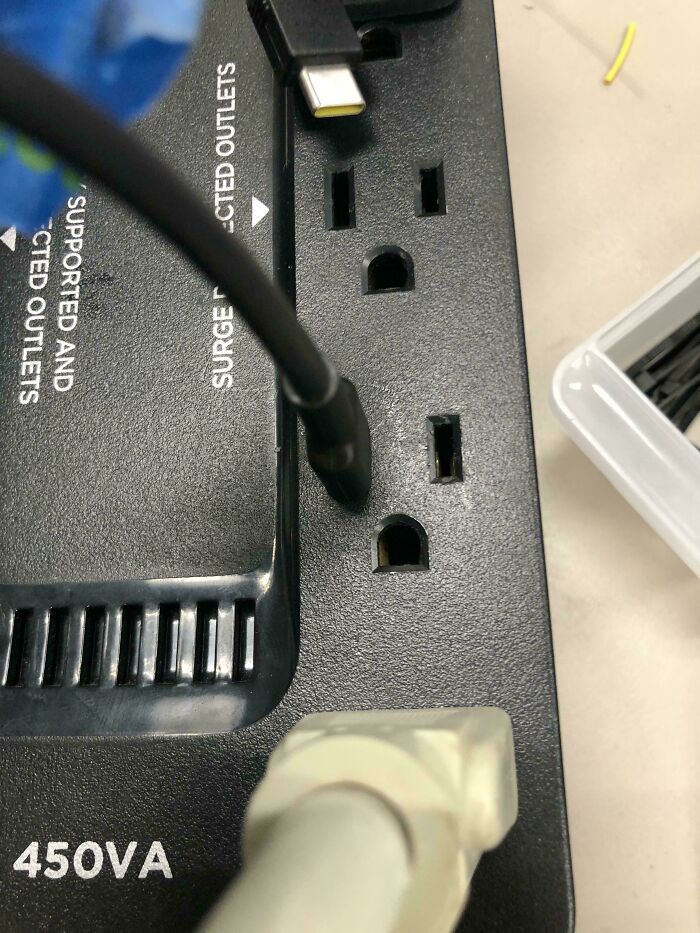 Tech support worker dealing with incorrectly plugged power cords on a surge protector outlet.