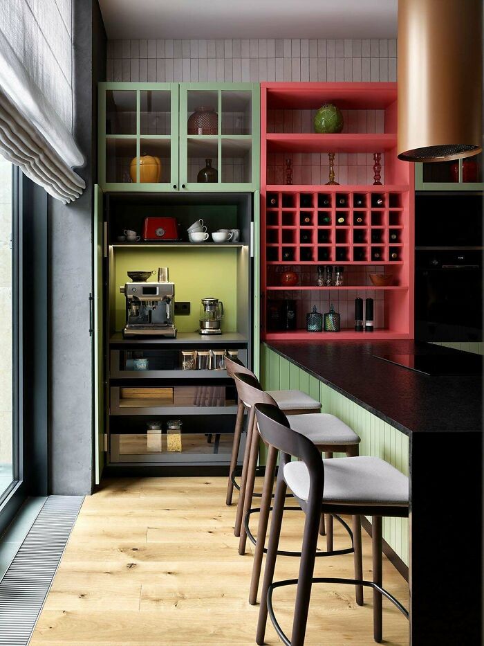 Modern kitchen with beautifully decorated homes featuring colorful cabinets and stylish bar stools by a large window.