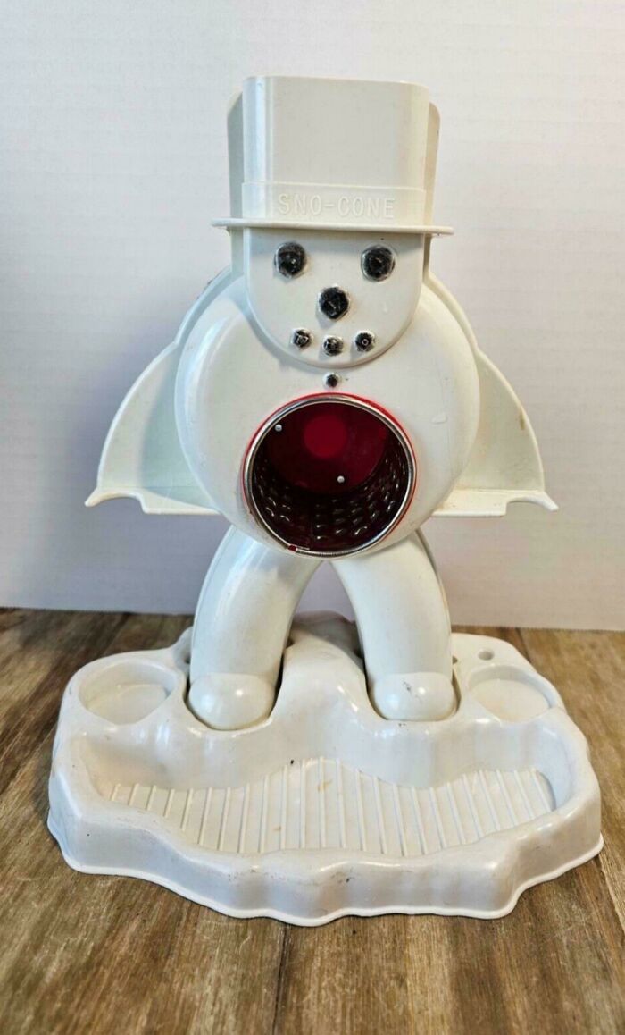 Vintage snowman Sno-Cone machine on wooden surface, evoking nostalgia.