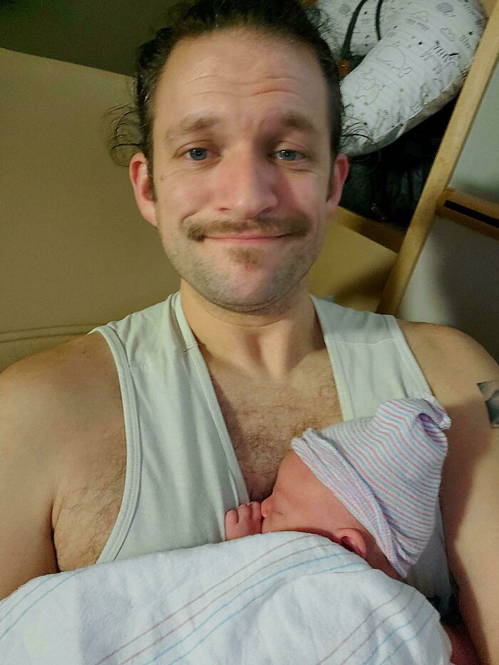 Father holding newborn baby wrapped in a blanket, capturing a wholesome dad parenting moment.