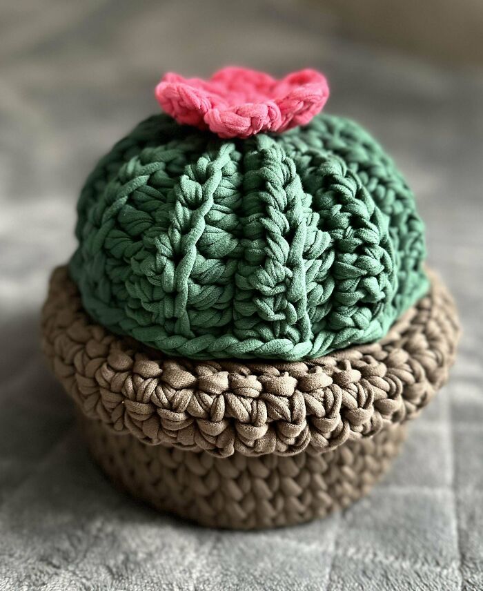 Crochet masterpiece of a cactus-shaped container with a pink flower, showcasing detailed crochet work and texture.