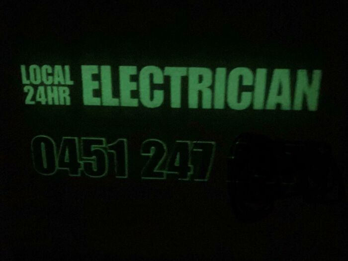 Glowing green local 24-hour electrician sign showing phone number in the dark, showcasing clever design innovation.
