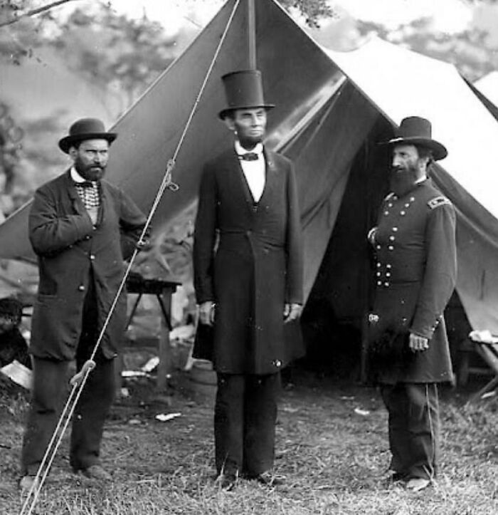 Rare historical photo of three men in 19th-century attire standing in front of a tent.