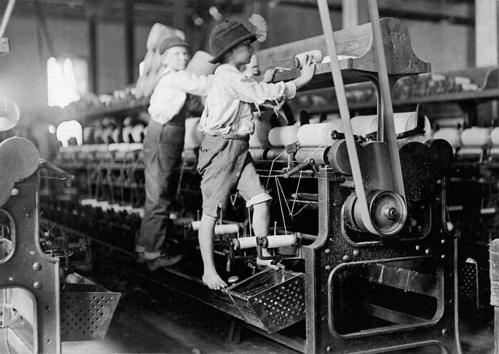 Children working on industrial machines in a factory, showcasing rare historical labor practices.