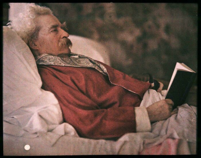 Rare historical photo, elderly man with white hair in bed, wearing red robe, reading a book.