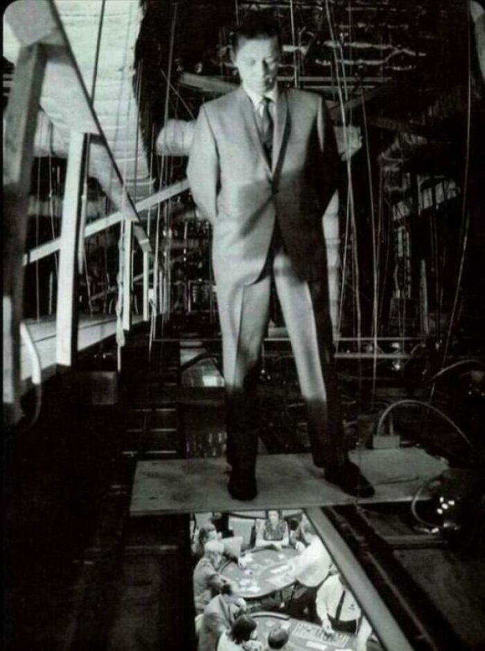 Man in a suit stands on a platform above a casino table, showcasing rare historical photo perspective.