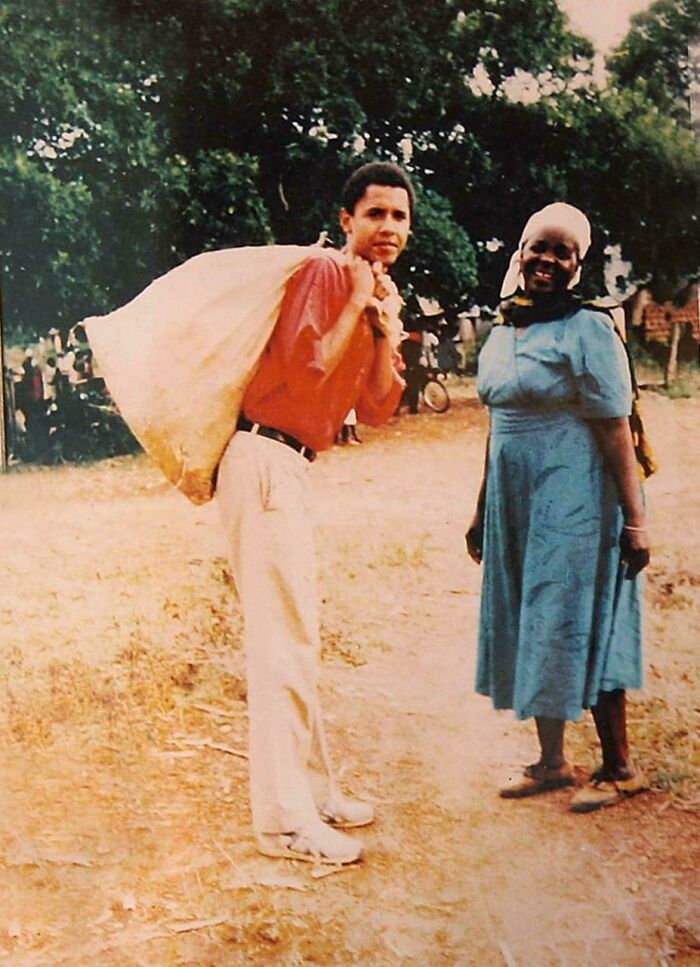 Young man carries a sack over his shoulder, standing next to a smiling woman in a village setting, conveying historical context.