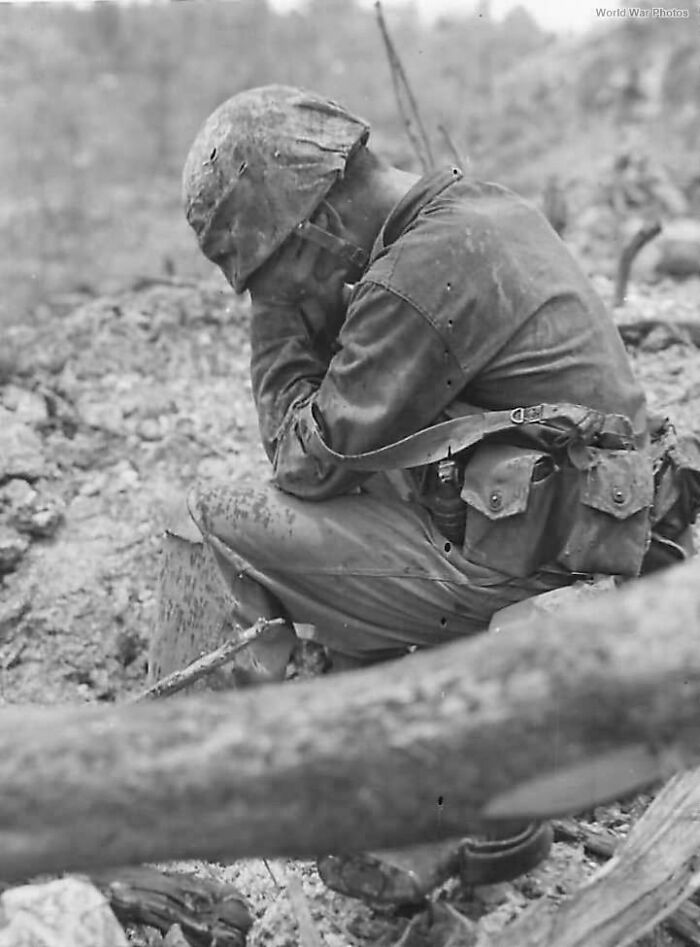 A soldier during WWII, sitting with head down, capturing a rare historical moment.