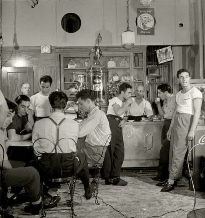 Historical photo of men in a vintage cafe, engaging in conversation, providing a glimpse into past social settings.
